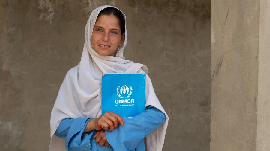 Una chica que lleva puesto un hijab ve a la cámara mientras sujeta un libro